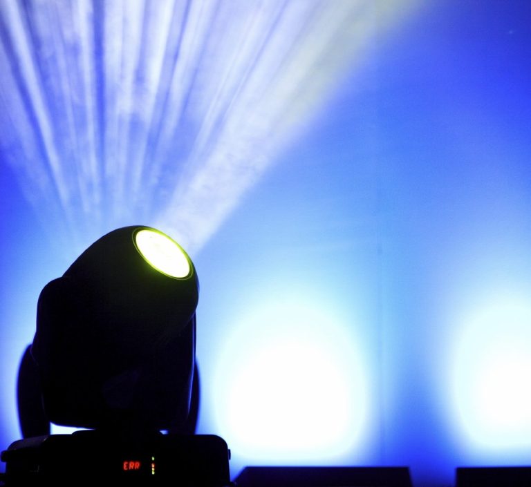 Moving Head strahlt Lichtstrahlen auf eine blaue Hintergrundfläche.