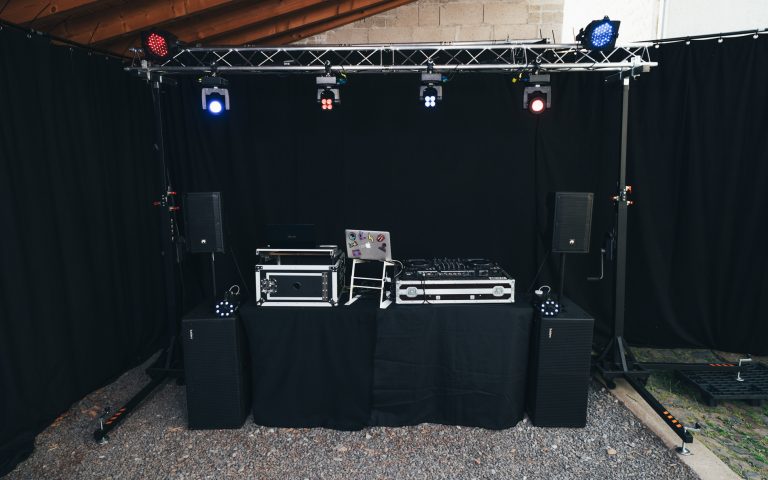 Veranstaltungstechnik DJ-Setup mit Lautsprechern und Lichttechnik vor schwarzem Hintergrund.