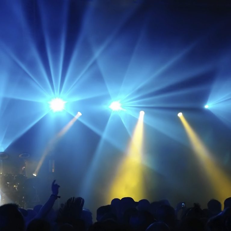 Intensive Lichter show mit blauen und gelben Scheinwerfern vor Publikum.