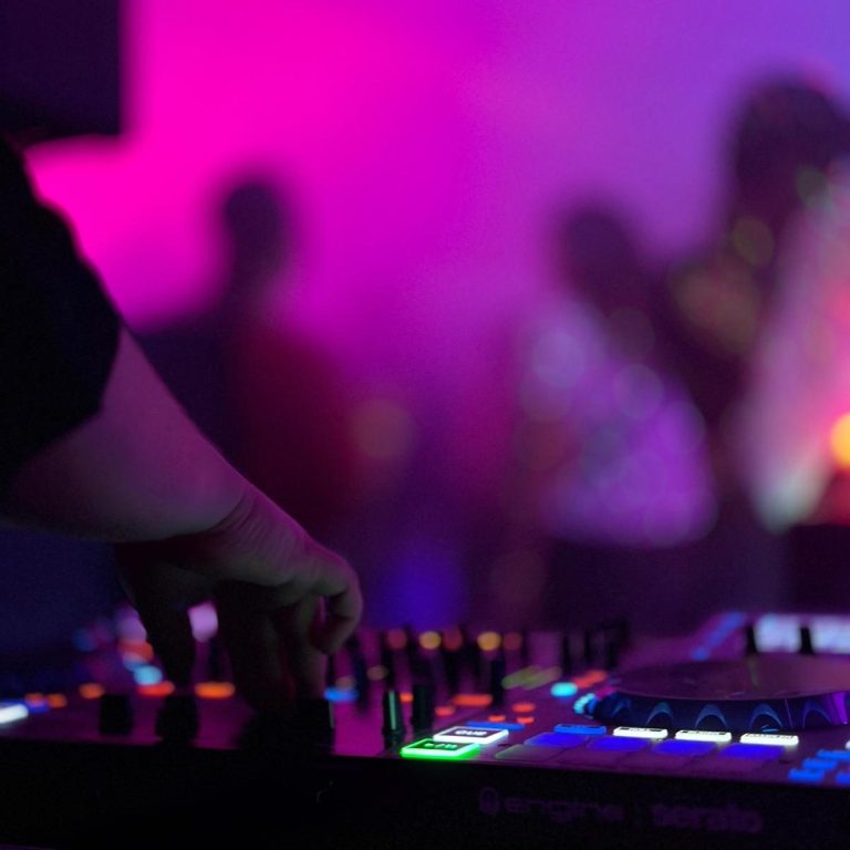 DJ-Mixer in einer lebhaften Umgebung mit bunten Lichtern.